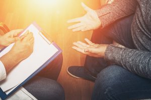 Psychologist listening to her patient and writing notes, mental health and counseling. Psychologist consulting and psychological therapy session concept, toned photo