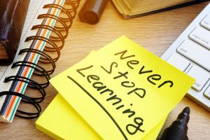 Never stop learning written on a memo stick. Lifelong learning concept.