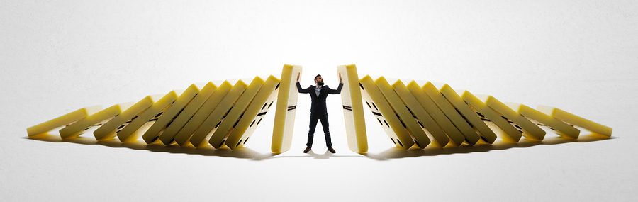 The man stops the falling dominoes. Concept of crisis management.